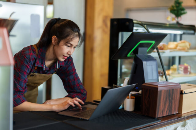 Close-up store owner smiling face when typing on laptop computer, because they are responding customer chats that come order bakery online, is happy that there are many orders coming in.